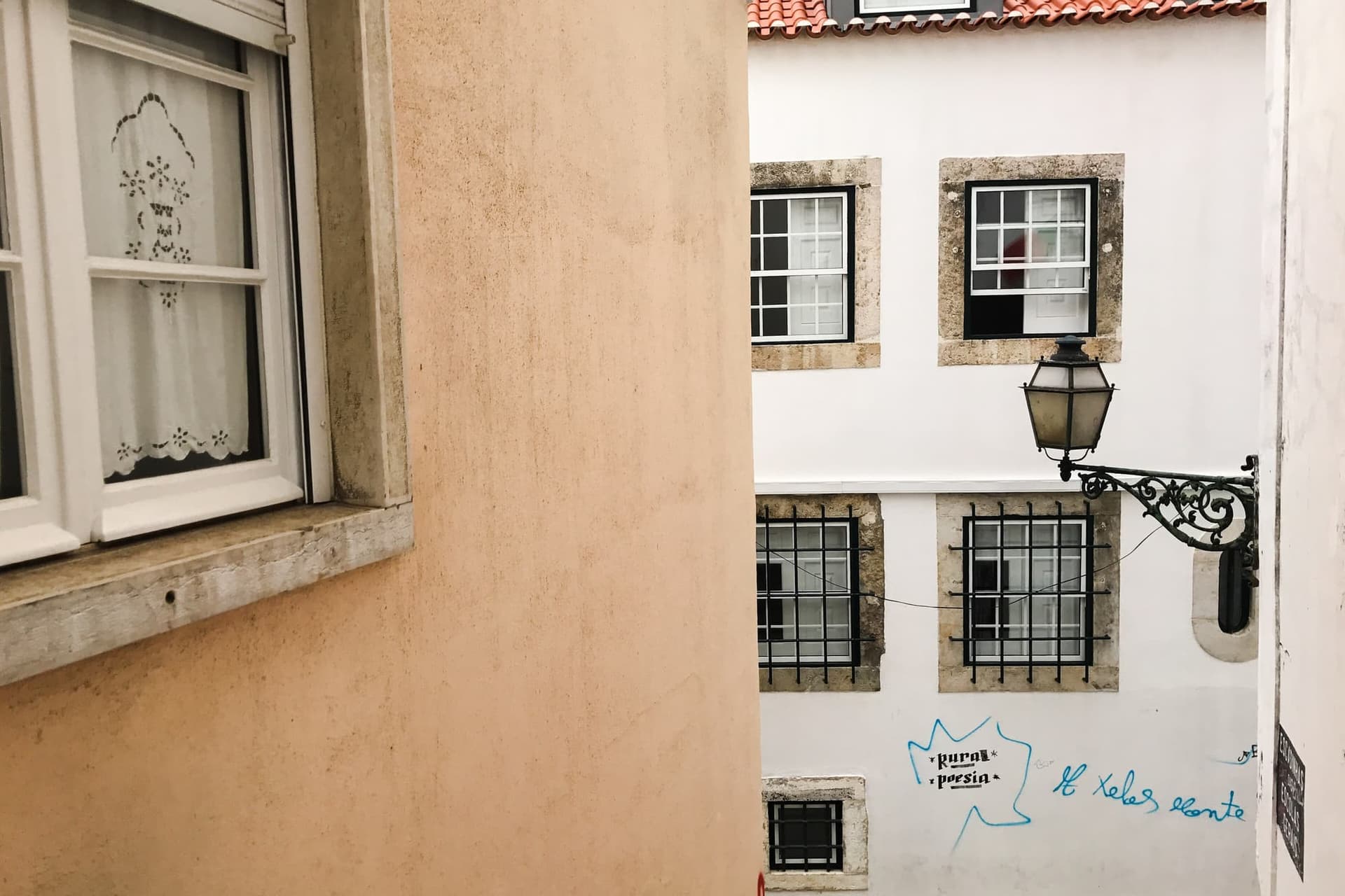 A steep, narrow Alfama lane between tall houses, washing strung between the balconies above.