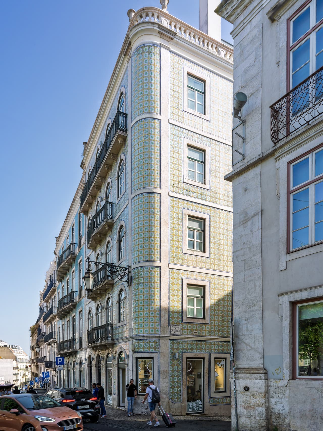 A Lisbon building front covered in blue and white patterned azulejo tiles with small iron balconies.