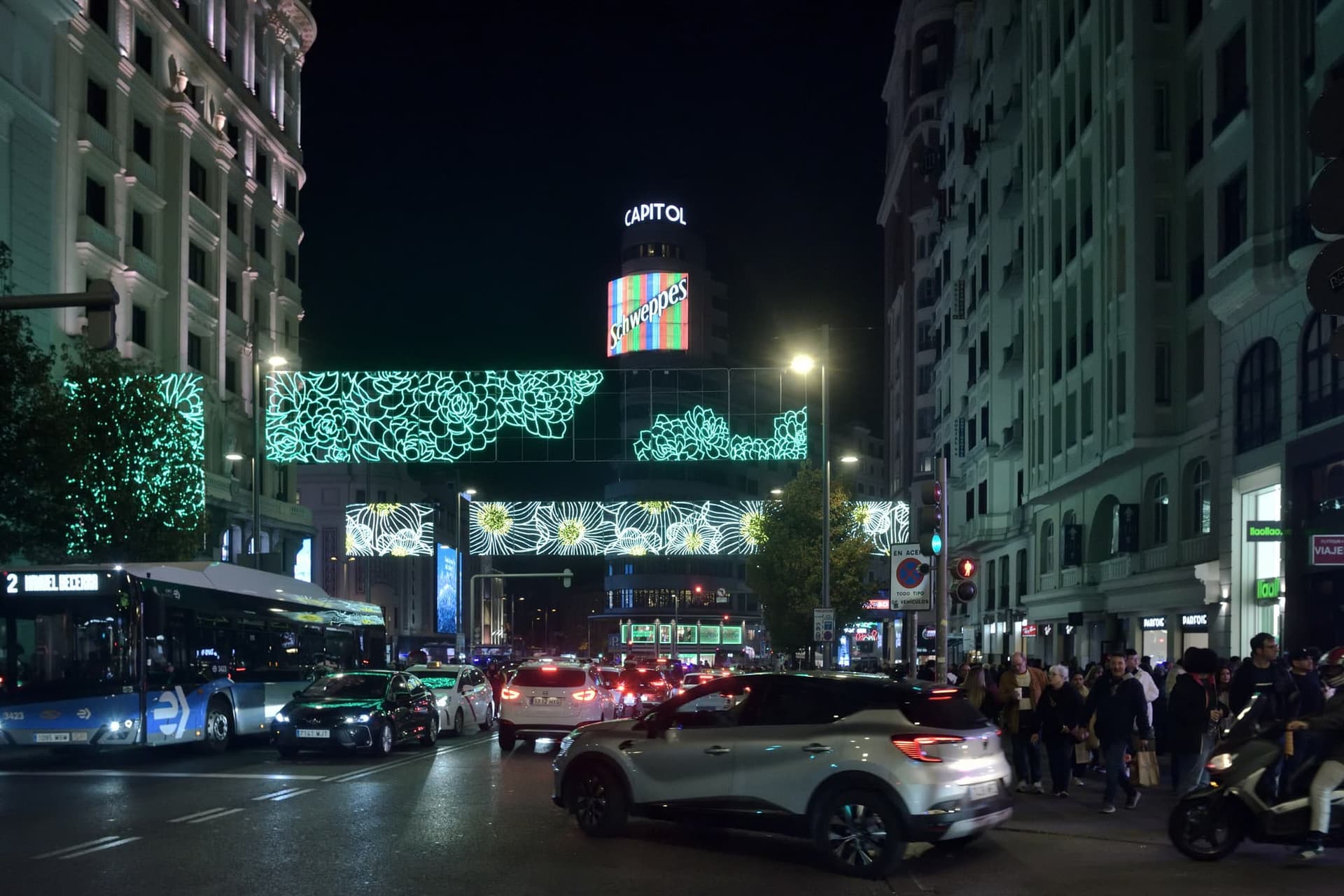 The curve of Madrid's Gran Vía at dusk, early twentieth-century blocks lit up along both sides of the street.